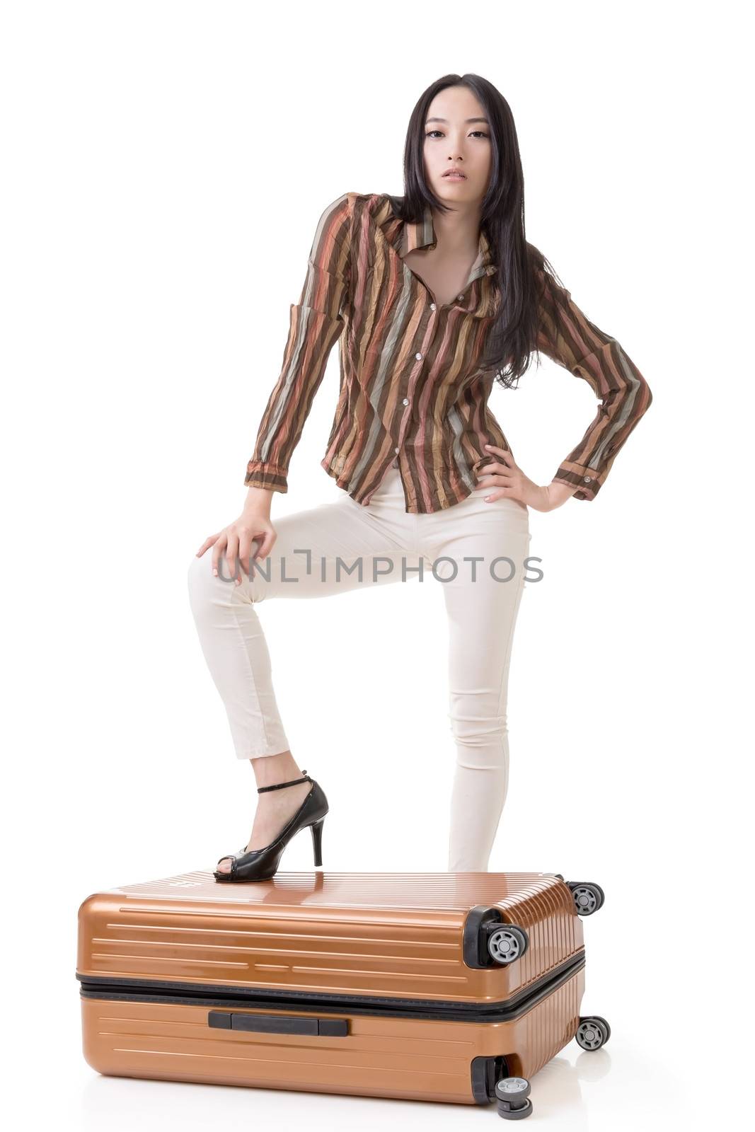 Modern Asian woman stand on a luggage, full length portrait on white background.