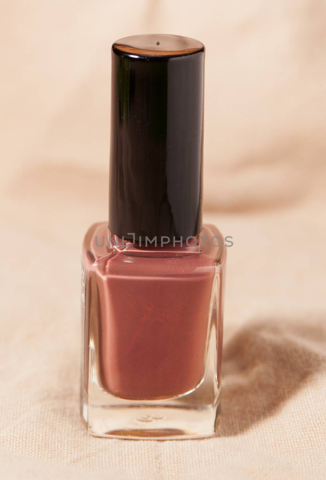 Small bottle of nail polish over beige background