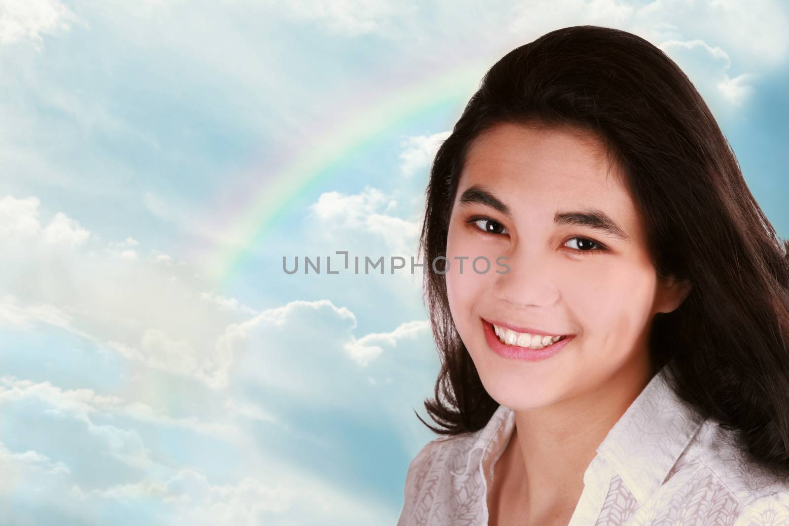 Teen girl against Beautiful clouds in blue sky with rainbow