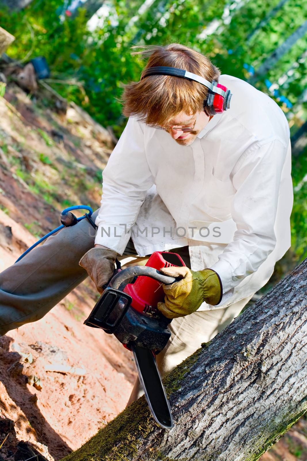 Caucasian man cutting down a tree with a chainsaw by jarenwicklund