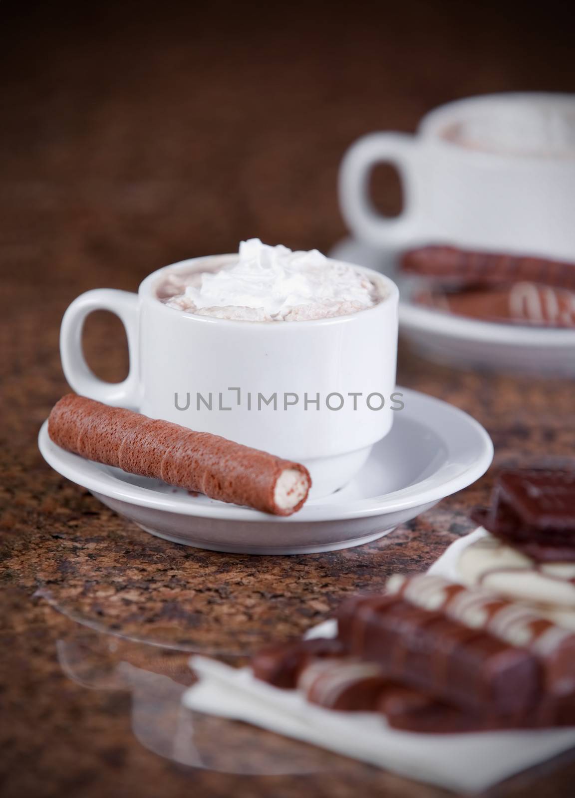 Two cups of coffee or hot cocoa with chocolates and  cookies on  by jarenwicklund