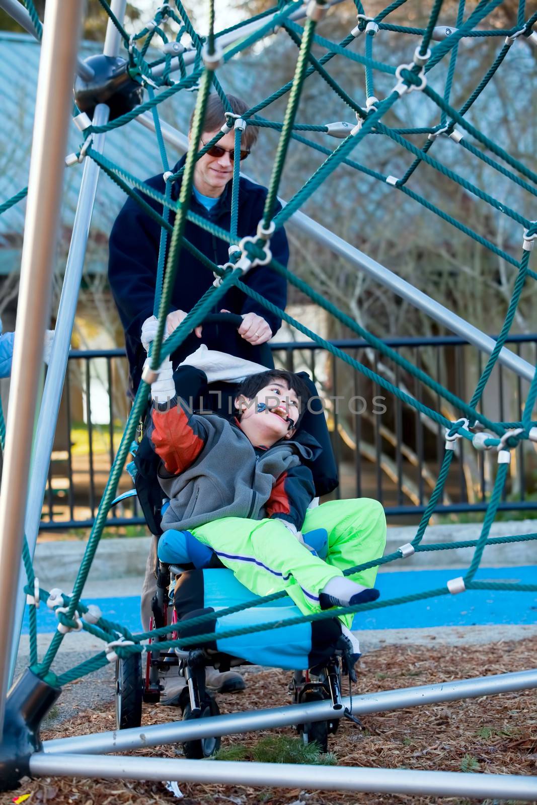 Father with disabled boy at the playground jungle gym