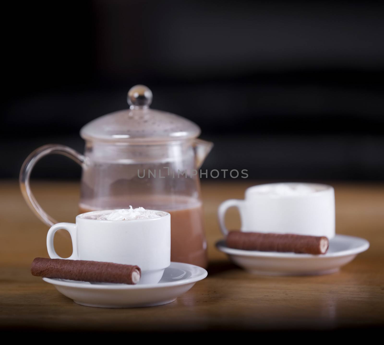 Two cups of coffee or hot cocoa with chocolates and  cookies on brown background 