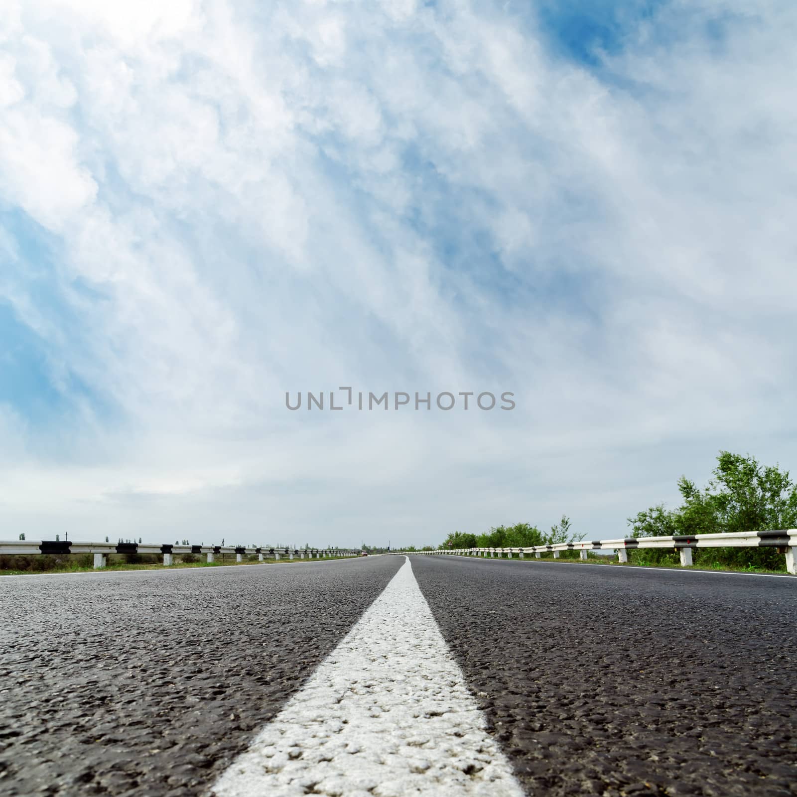 white line on asphalt road and clouds over it by mycola