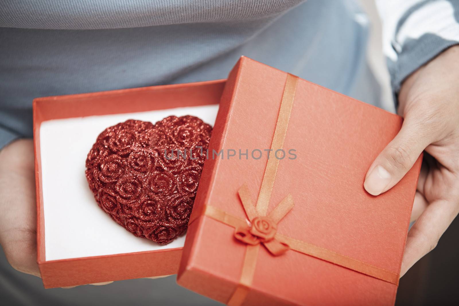Hands of woman opening gift box with heart