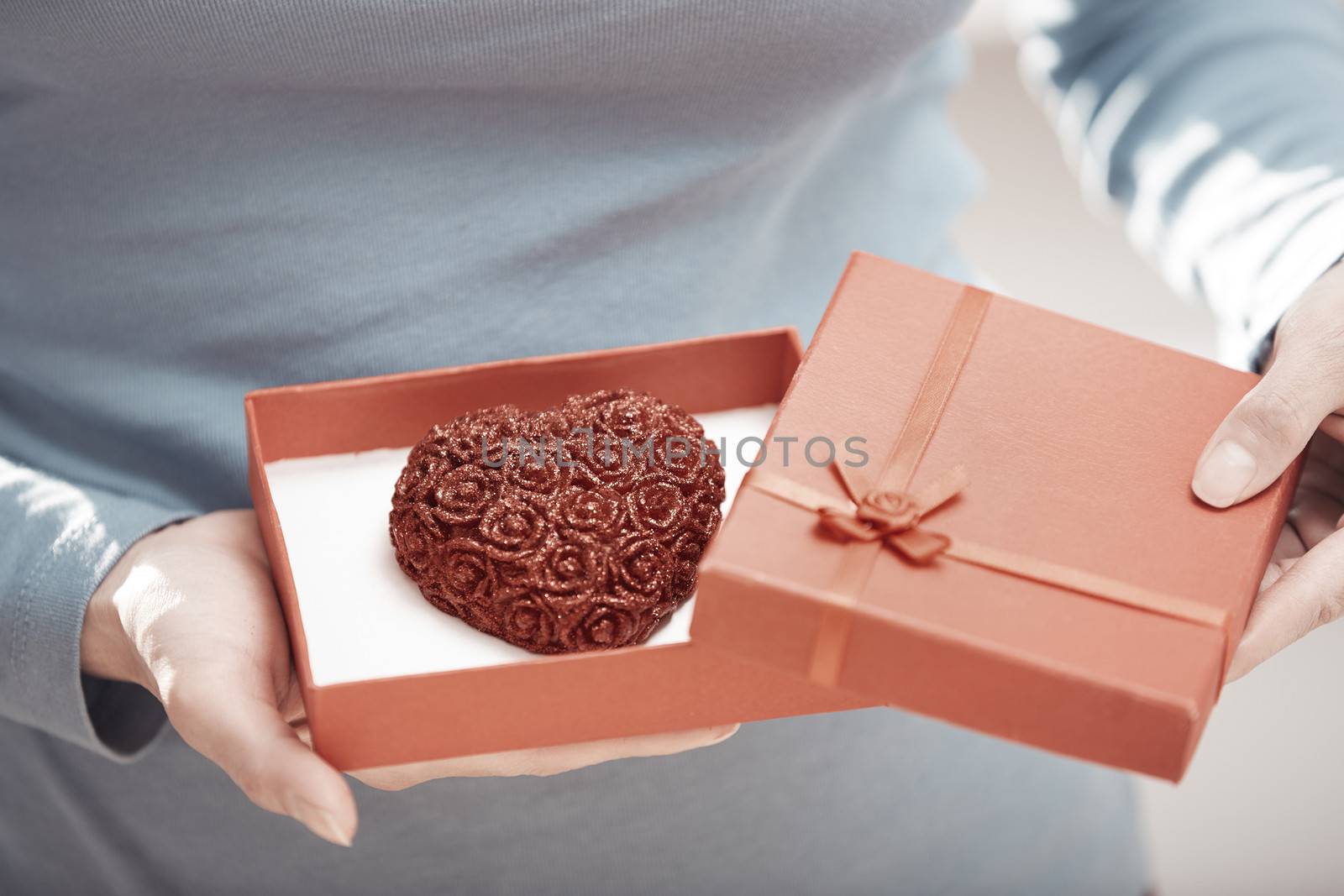 Hands of woman opening gift box with heart