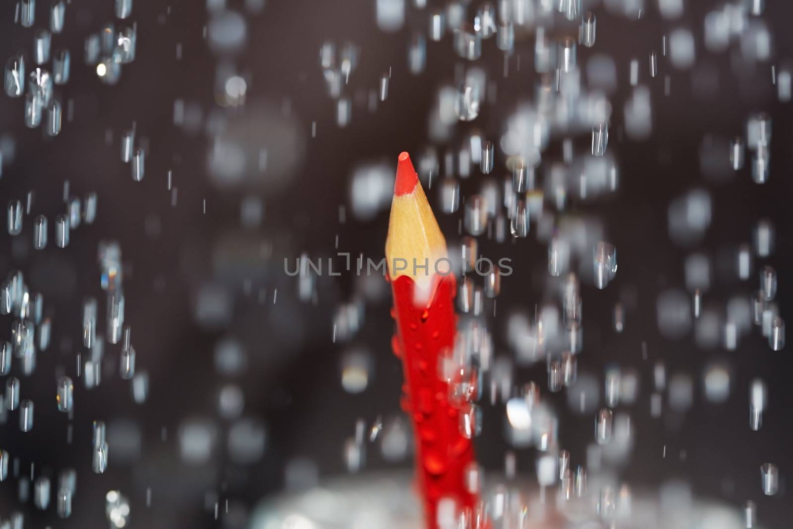 Red crayon under the rain. Close-up view