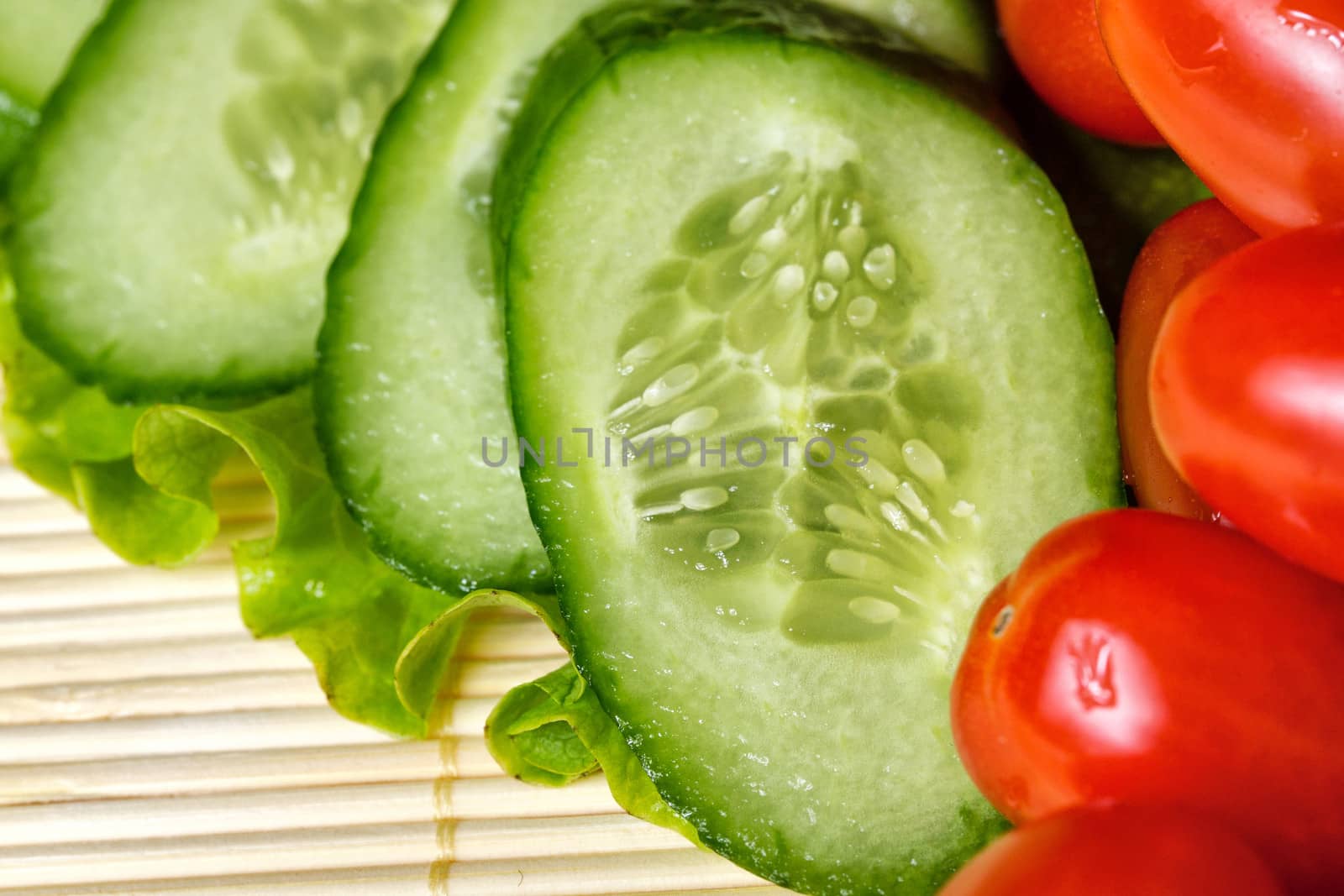 Ripe cherry tomatoes, cucumbers and lettuce closeup shot