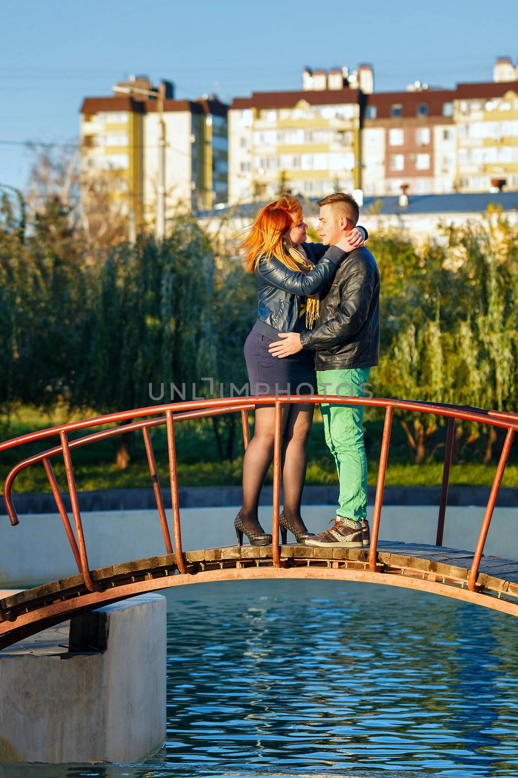 Young couple embracing standing on the bridge in the city park