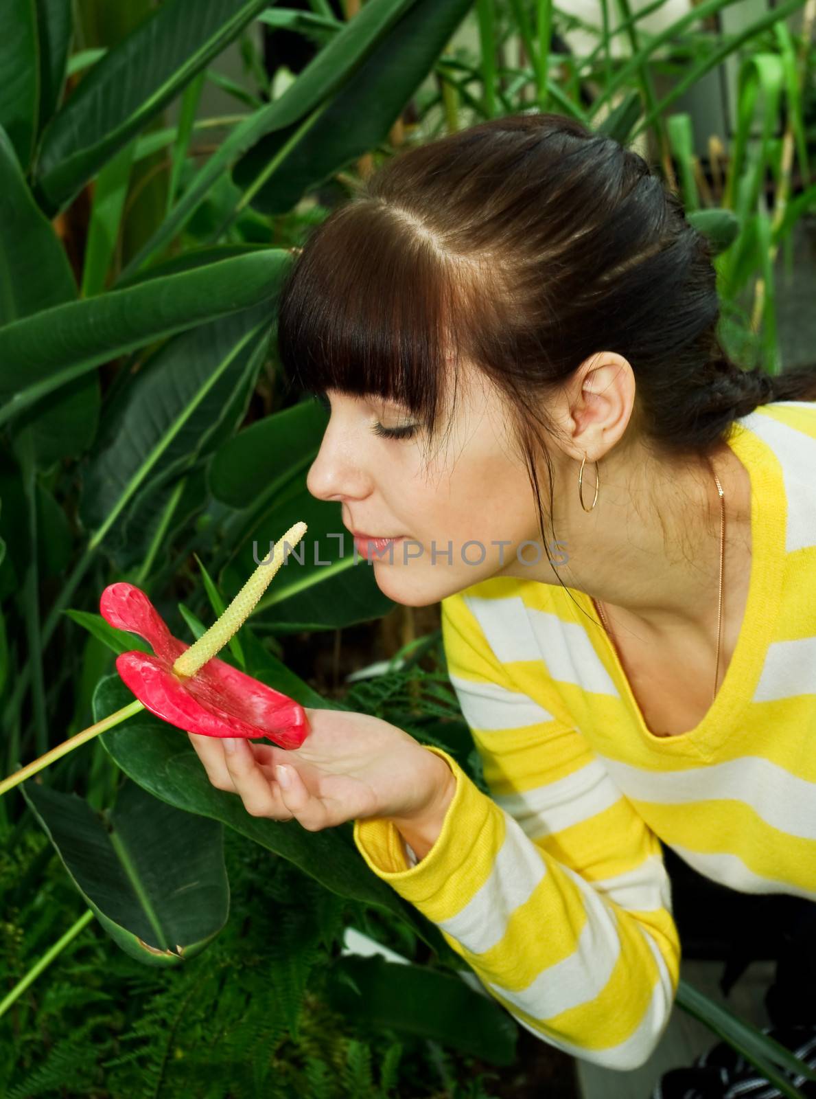 Young woman smelling red flower