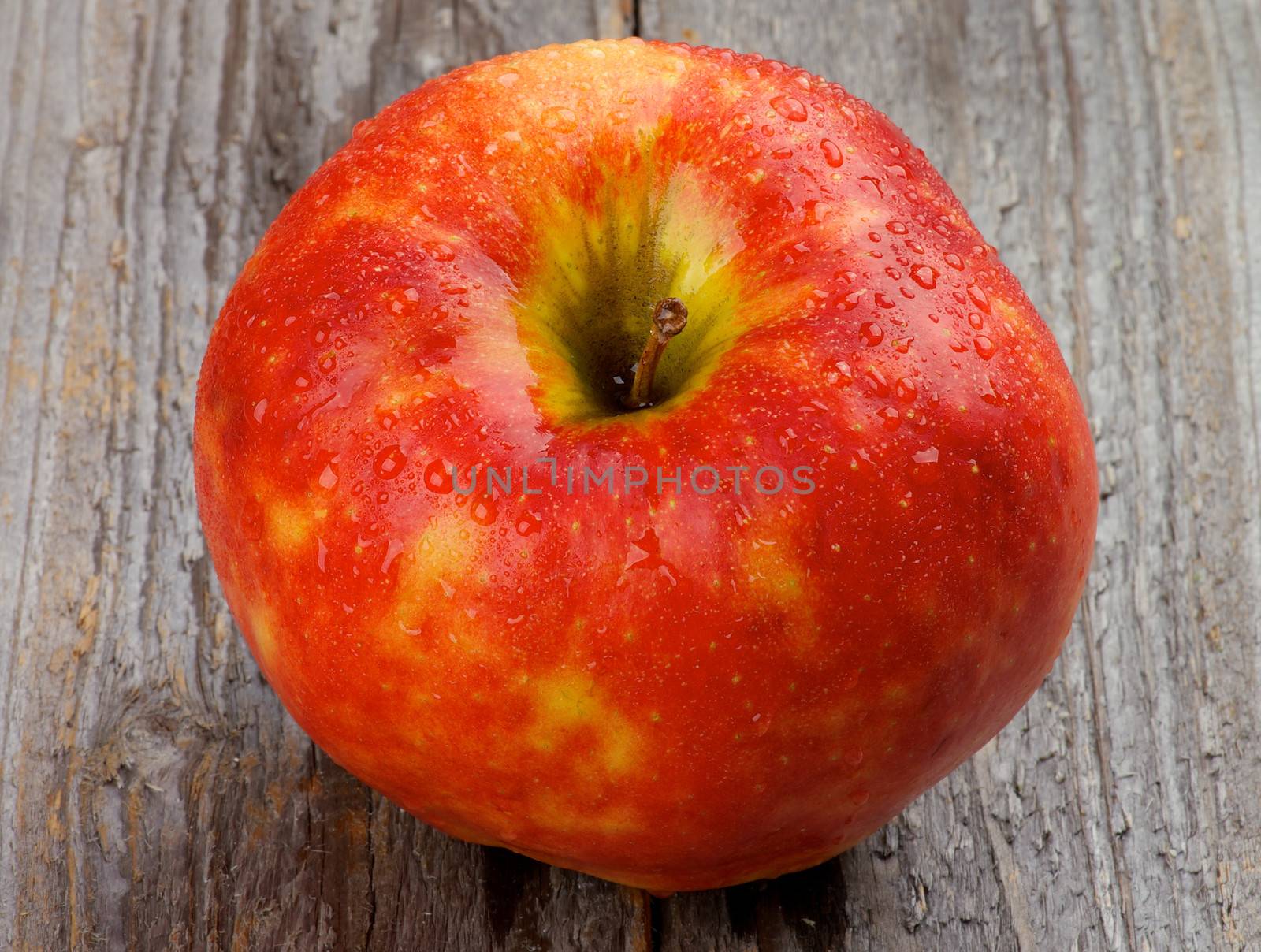 Delicious Red Apple with Water Droplets isolated on Rustic Wooden background