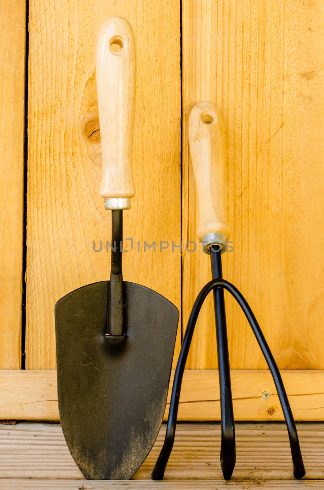Trowel and cultivator on wood background.