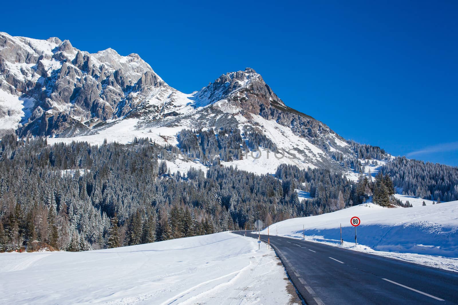Winter in the alps mountain. Asphalt road among snow.