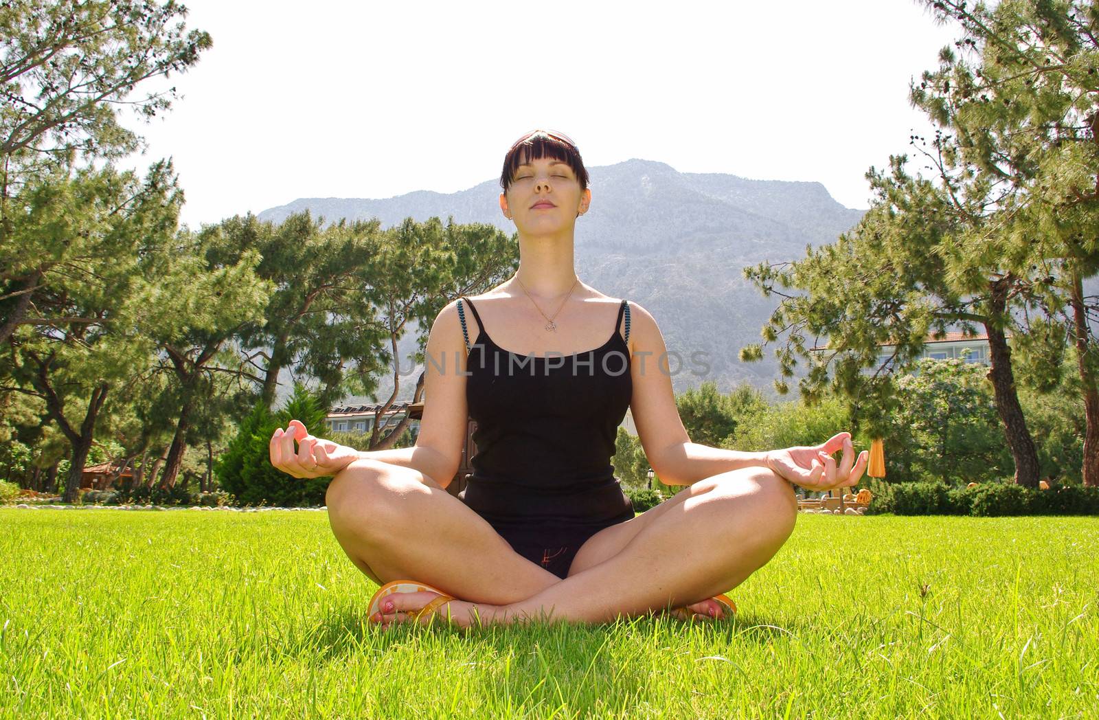 Young meditating woman on sitting grass