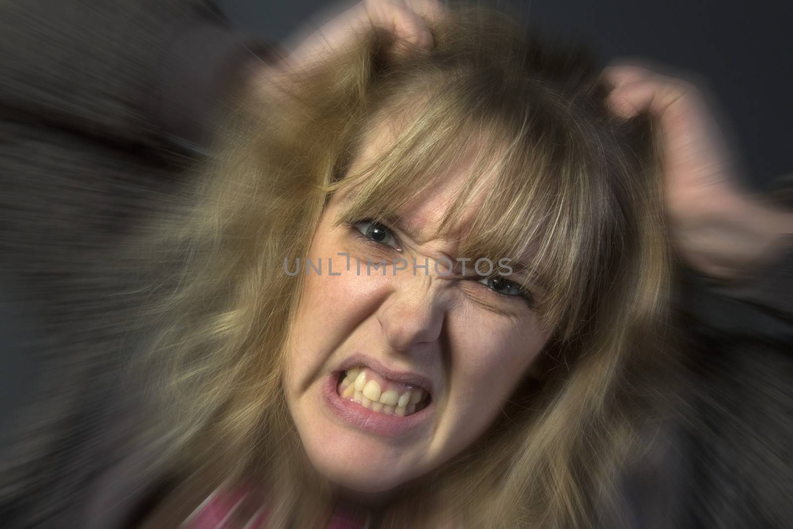 A very angry young woman tearing her hair out.