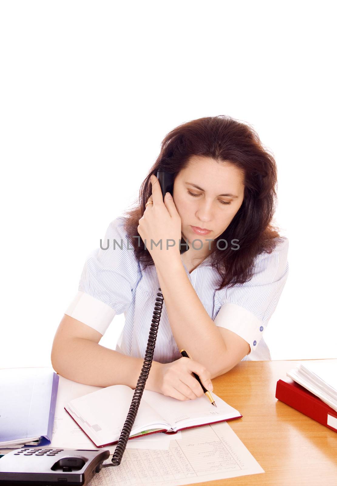 Portrait of a pretty business woman at office desk writing on document while talking on telephone