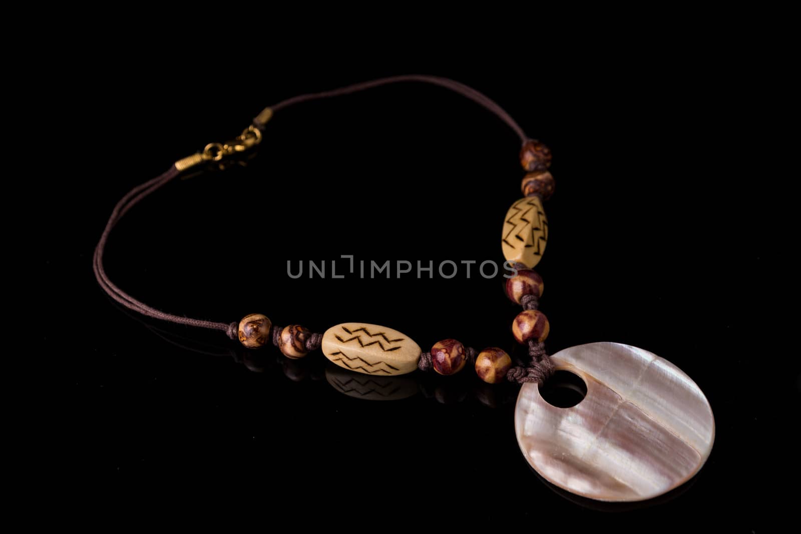 Simple shell necklace isolated on black background with light reflection