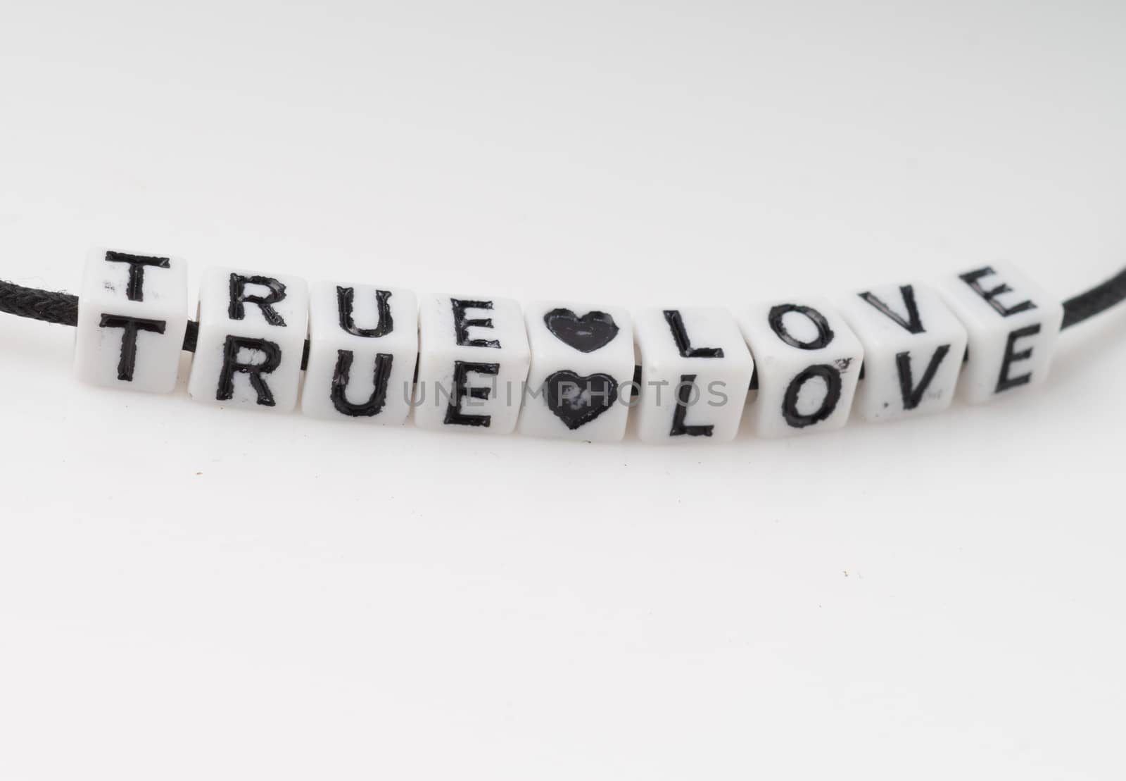 True love spelled in alphabed beads on white background