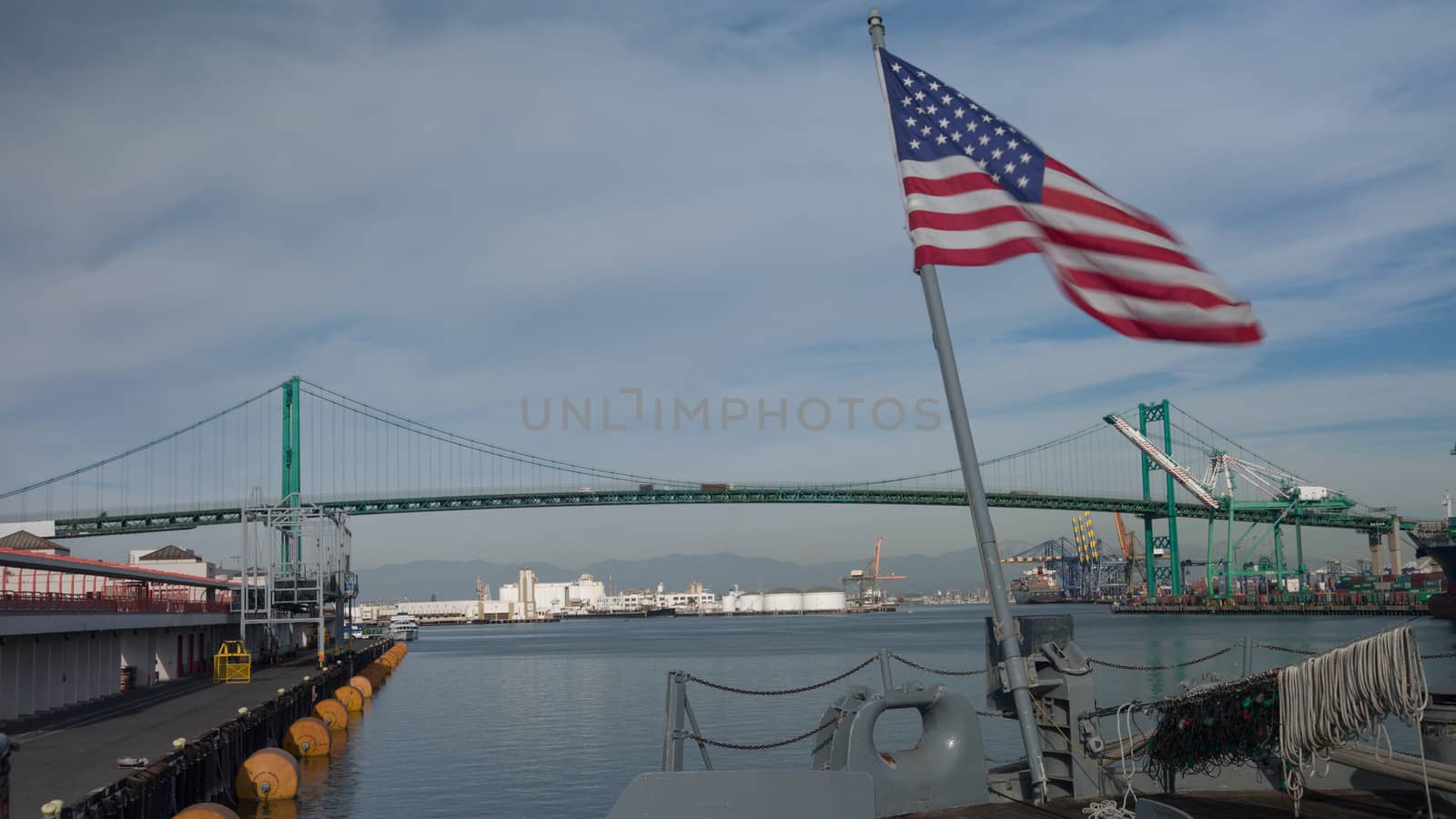 American Flag waving in wind with Vincent Thomas Bridge and Los Angeles Harbor in background