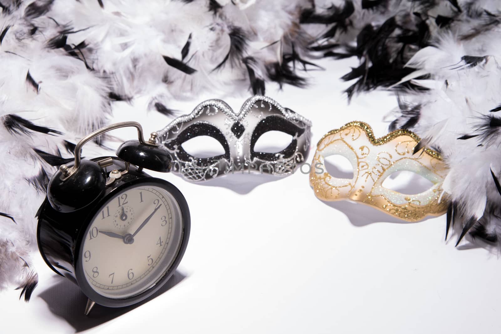 Time to celebrate. Alarm clock with Mardi Gras mask and feather boa
