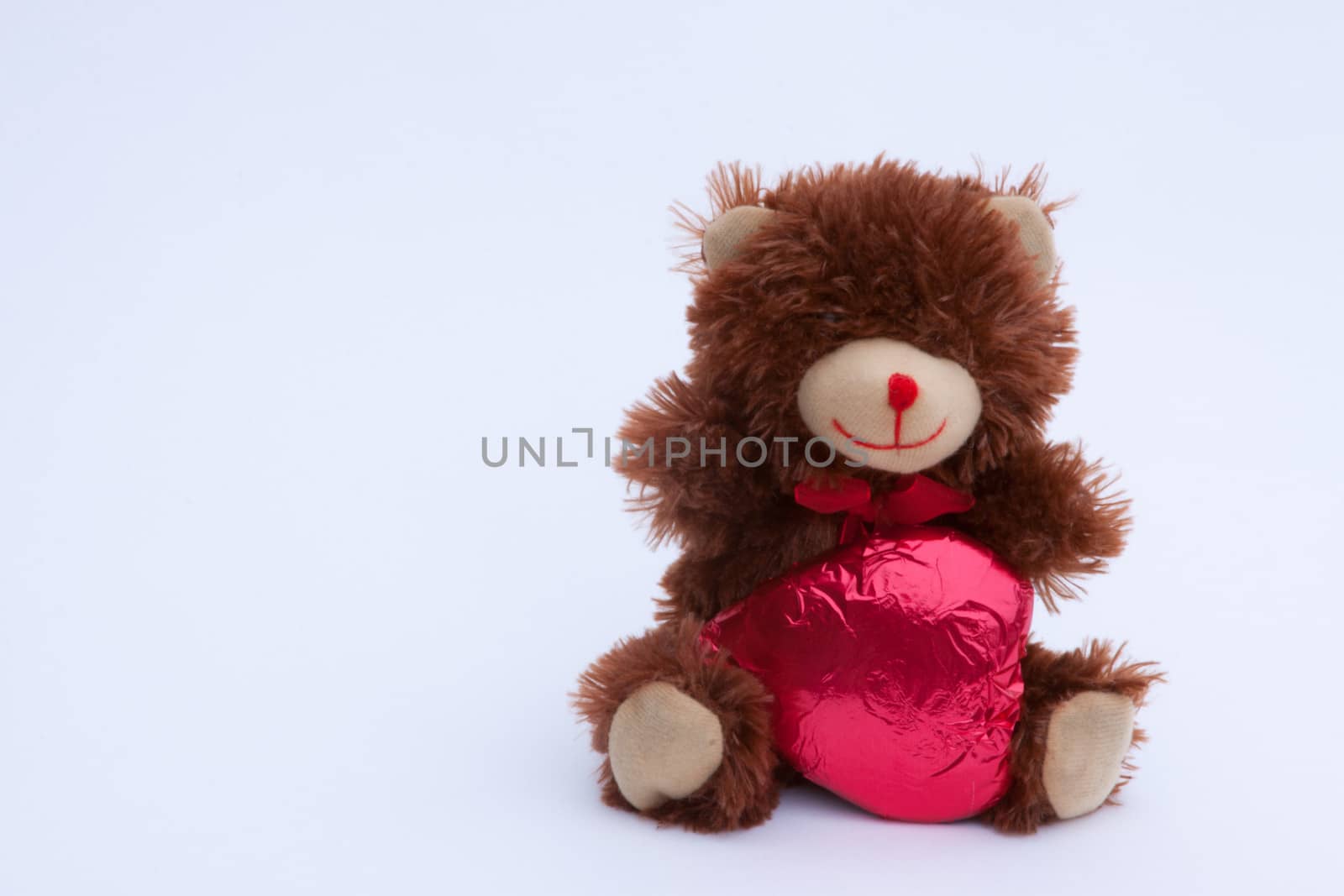 A Valentine's Day Teddy Bear with a red covered chocolate heart.