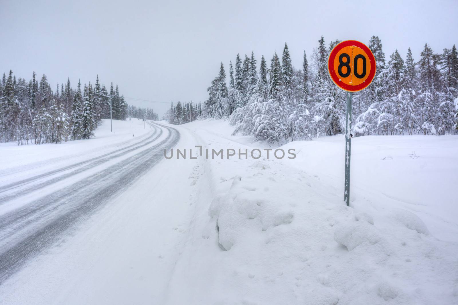 Warning traffic sign on snowy arctic winter road.