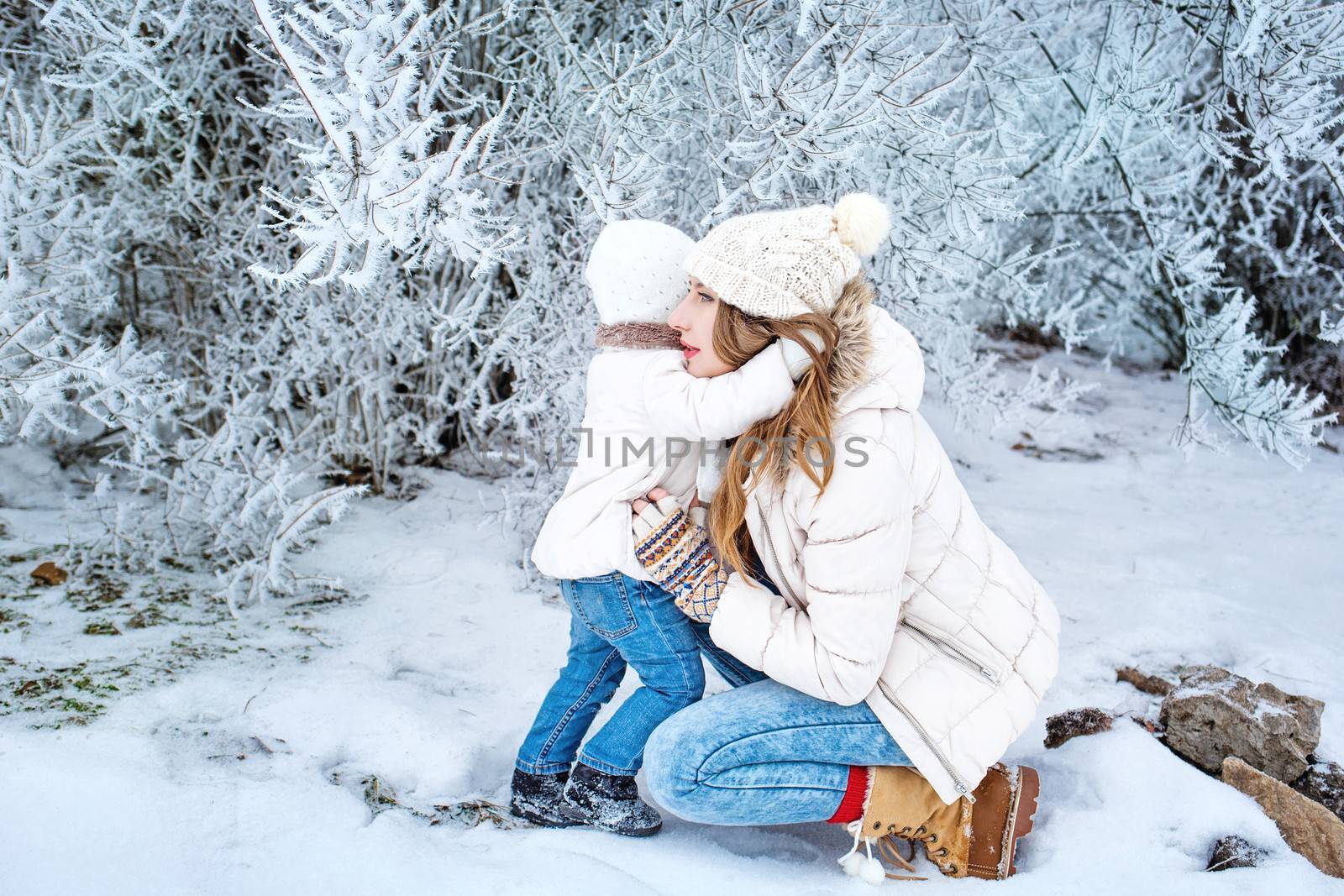 Young mother and daughter laughing for a walk in winter forest