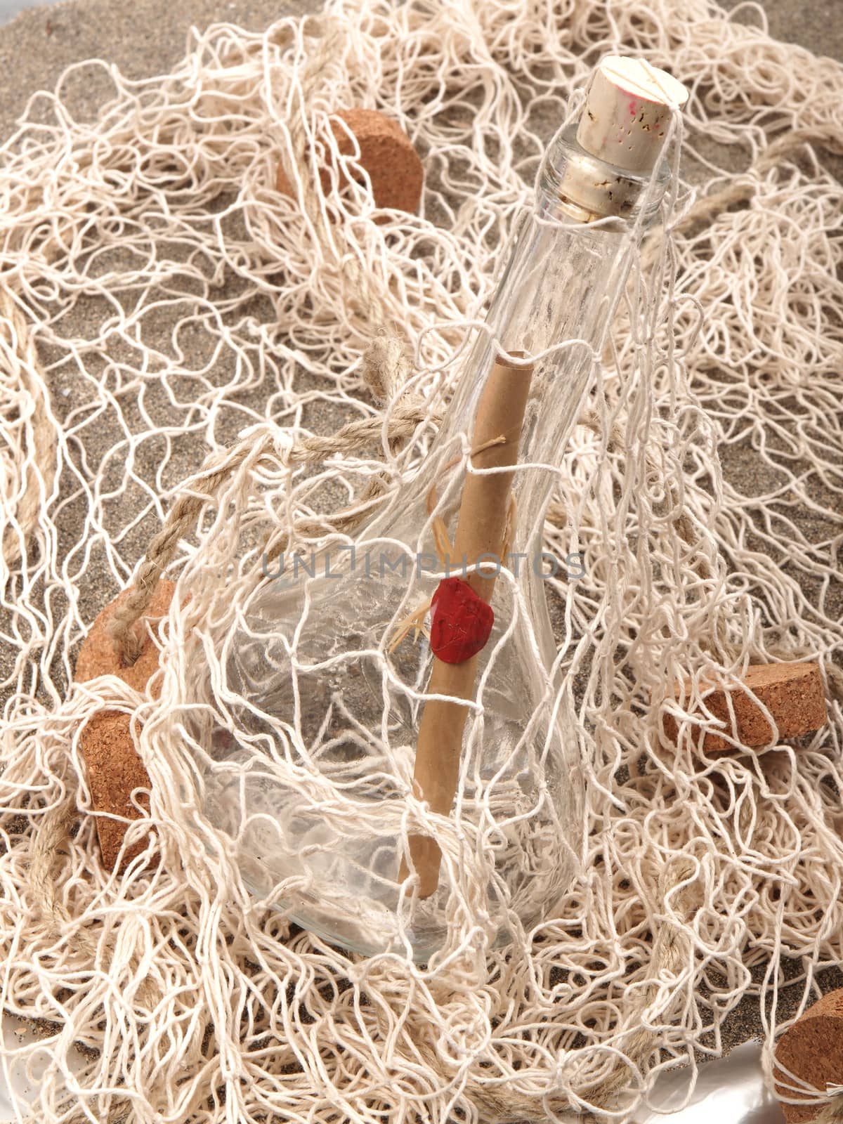 message in the bottle in the fishing net on the sand beach          