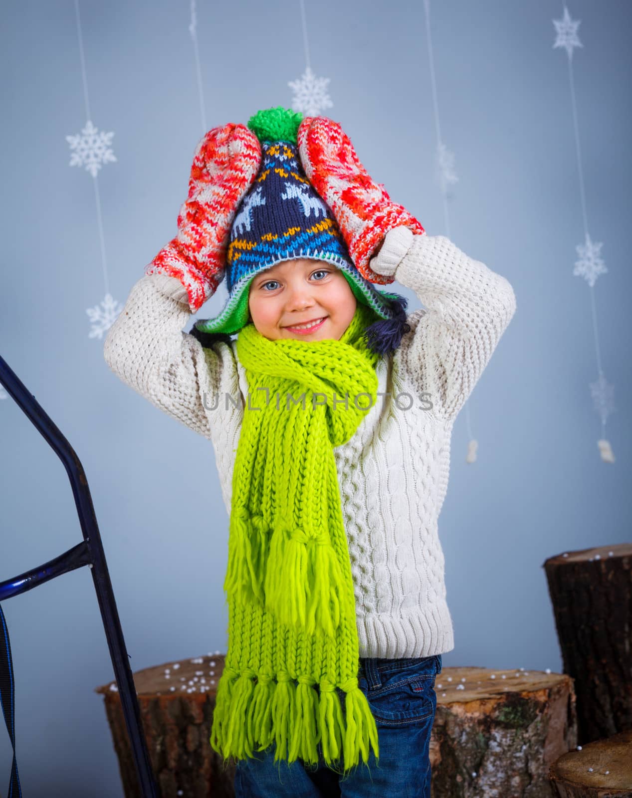 Winter Fashion. Portrait of adorable happy boy in winter hat gloves and sweater in studio.