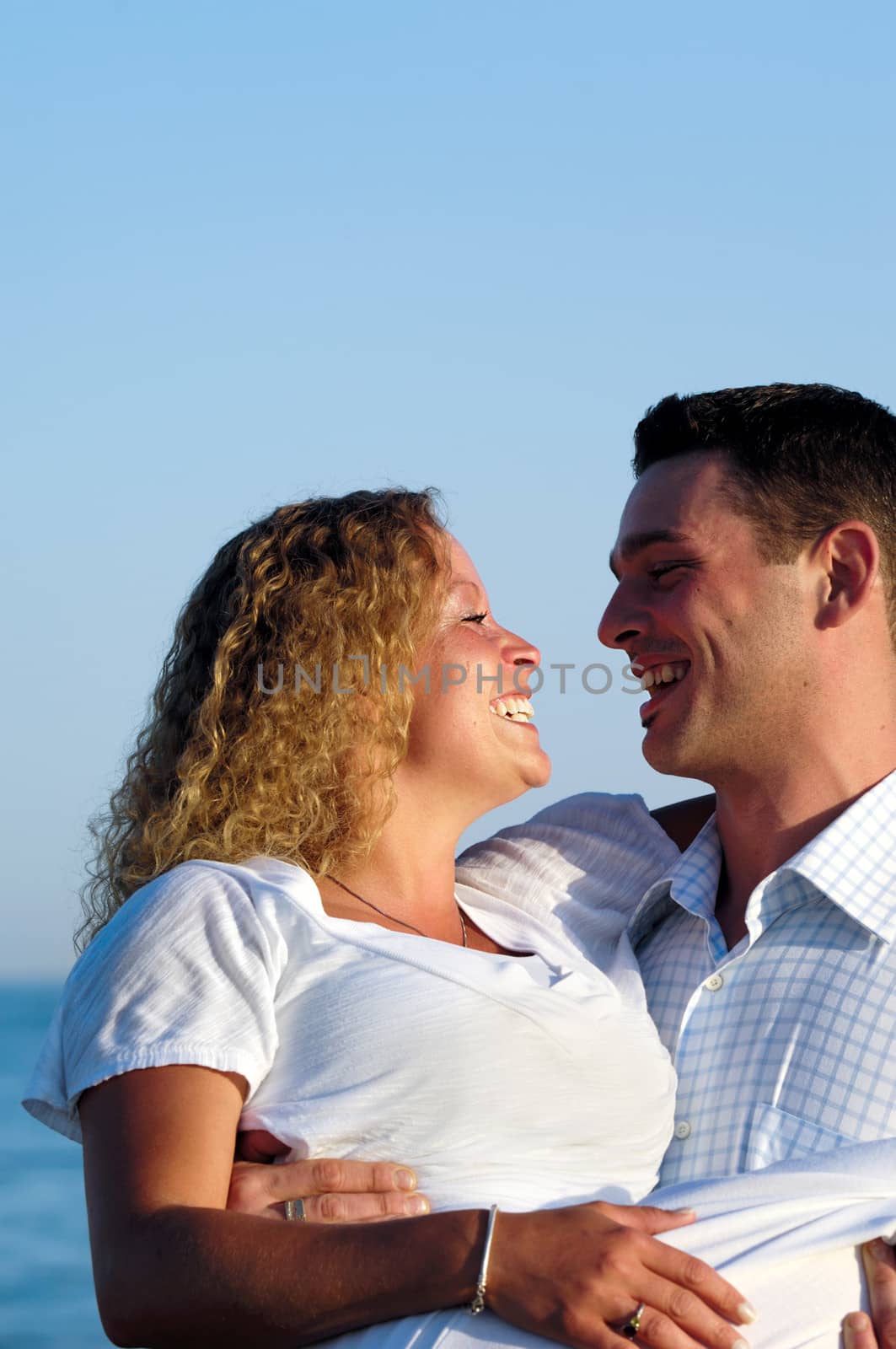 A happy woman and man in love at beach. The the young man is lifting his girlfrind.