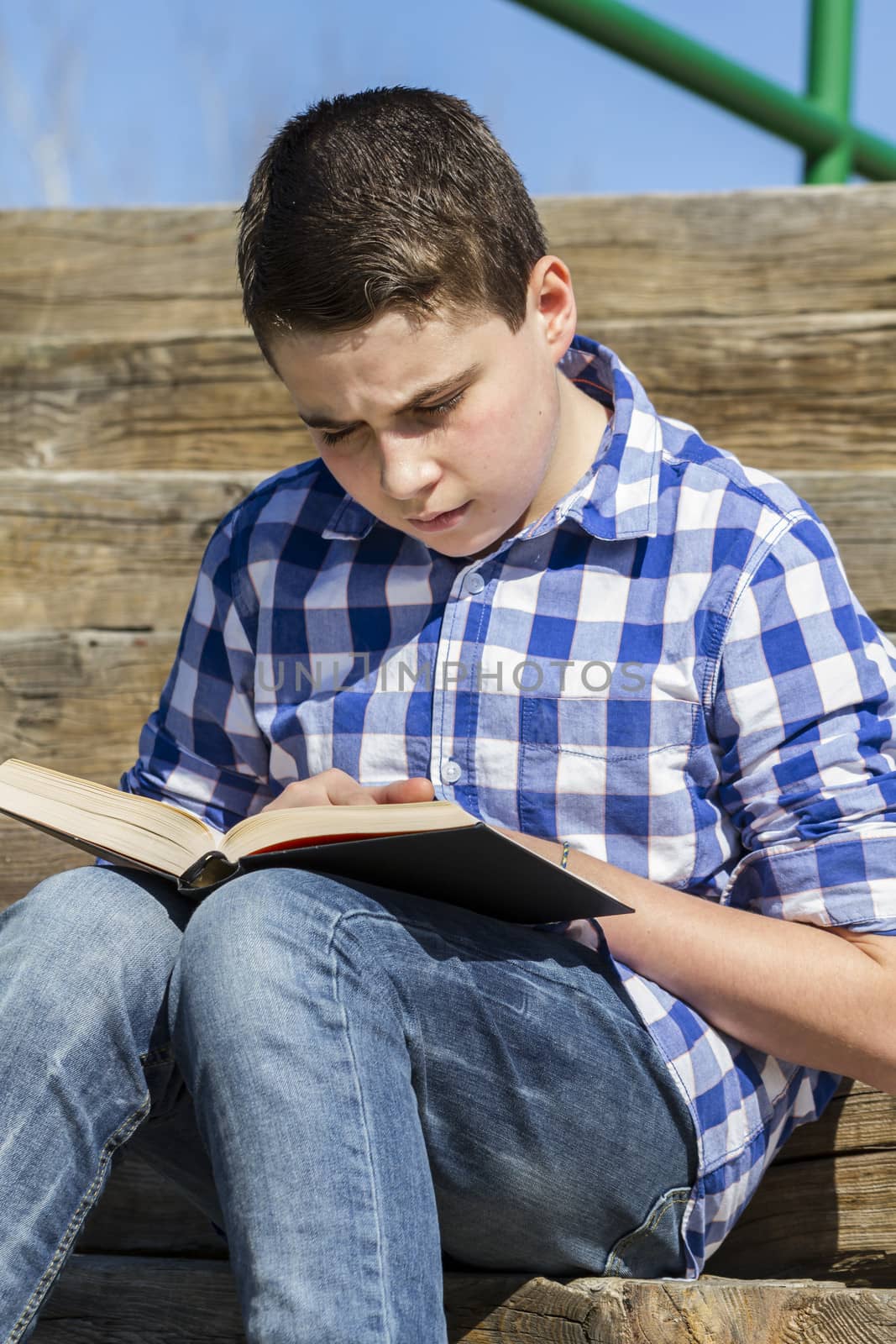 Leisure.Young boy reading a book in the woods with shallow depth of field and copy space