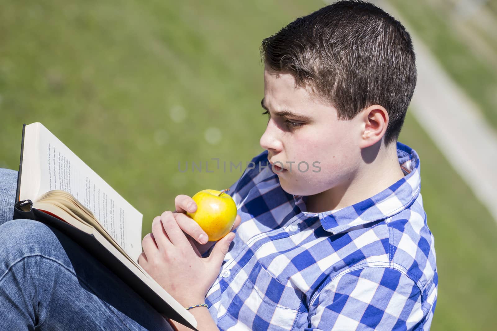 Looking.Young man reading a book in outdoor with yellow apple.