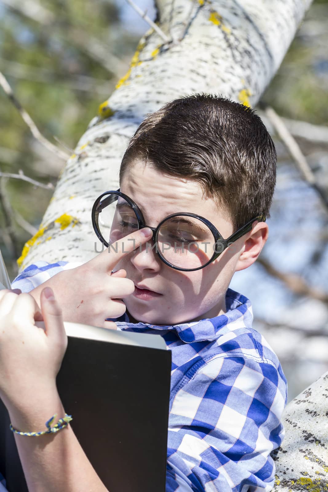 Huge glasses.Student boy reading a book in the woods with shallow depth of field and copy space