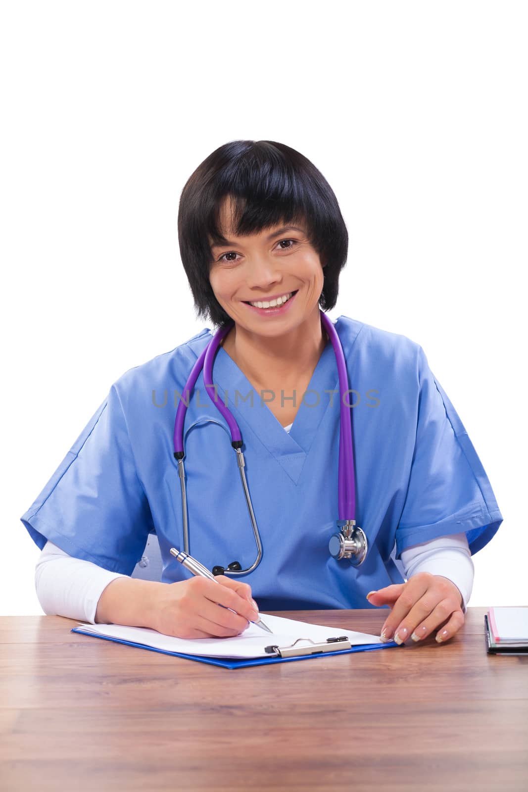 a smiling asian female doctor sitting at table and writing isolated