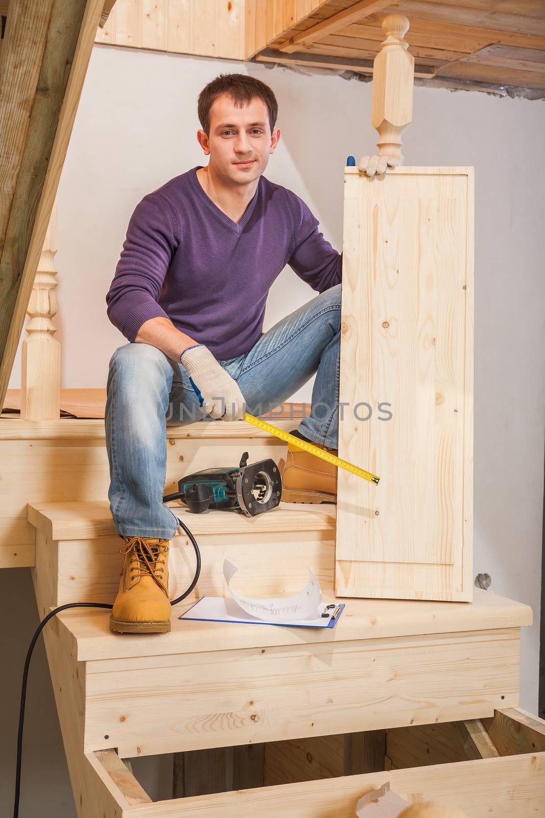 a young worker sitting on ladder and holding one step by mihalec