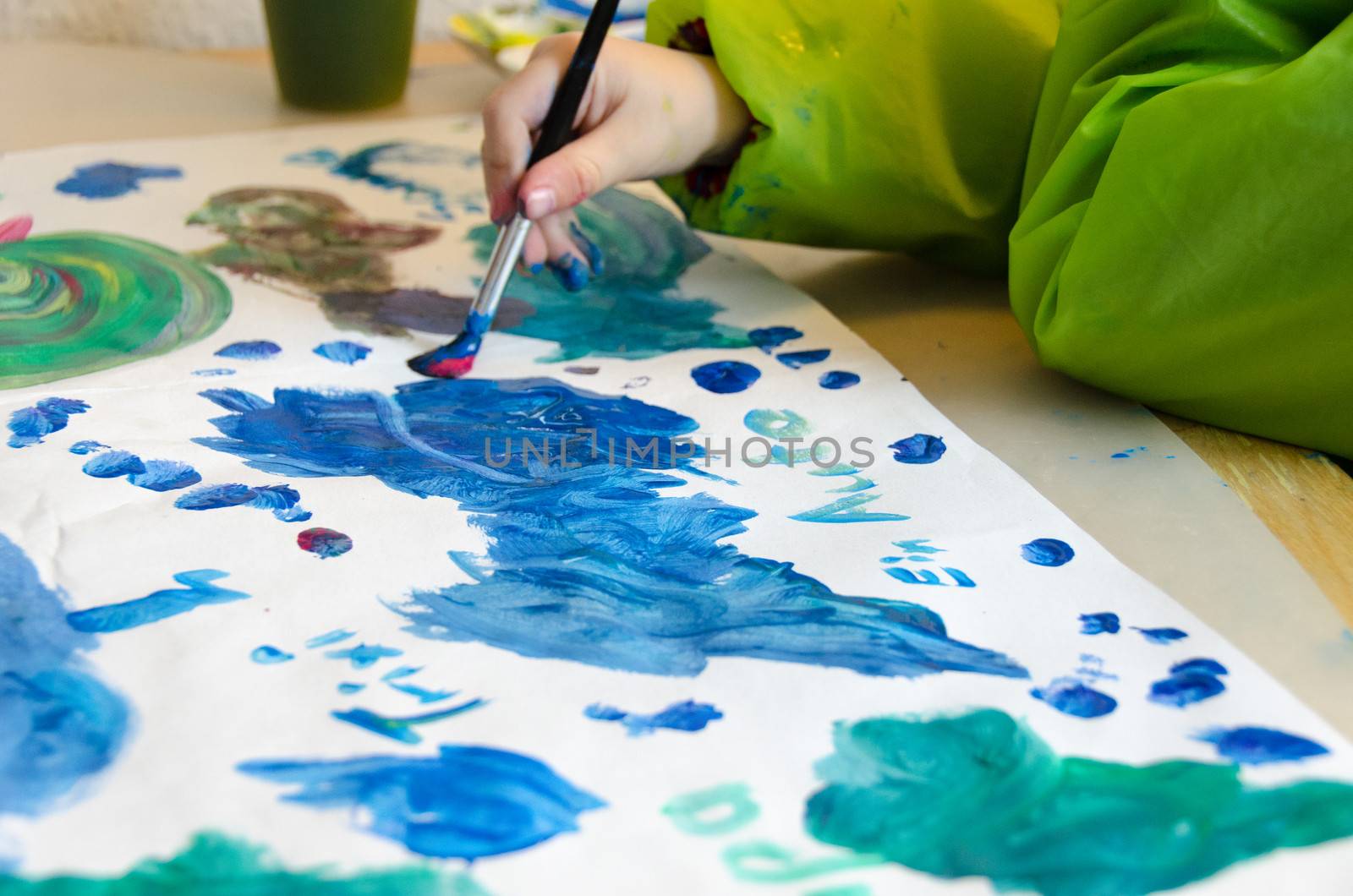 Child painting with an paint brush and water colors on paper