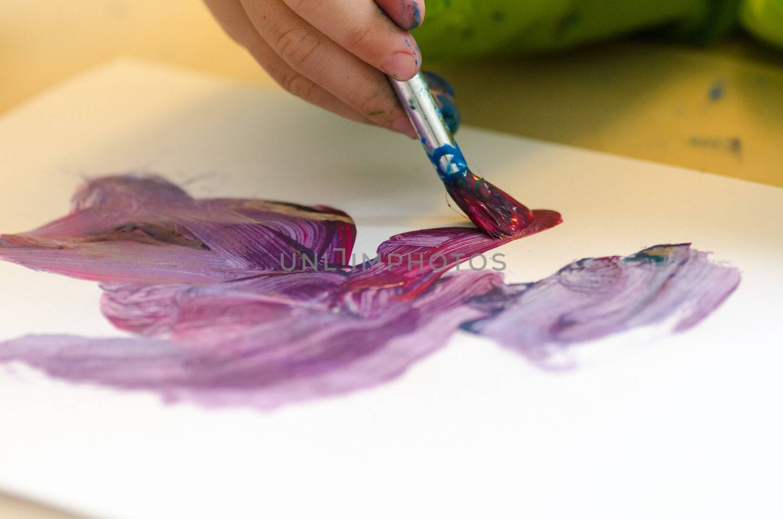 Child painting with an paint brush and water colors on paper