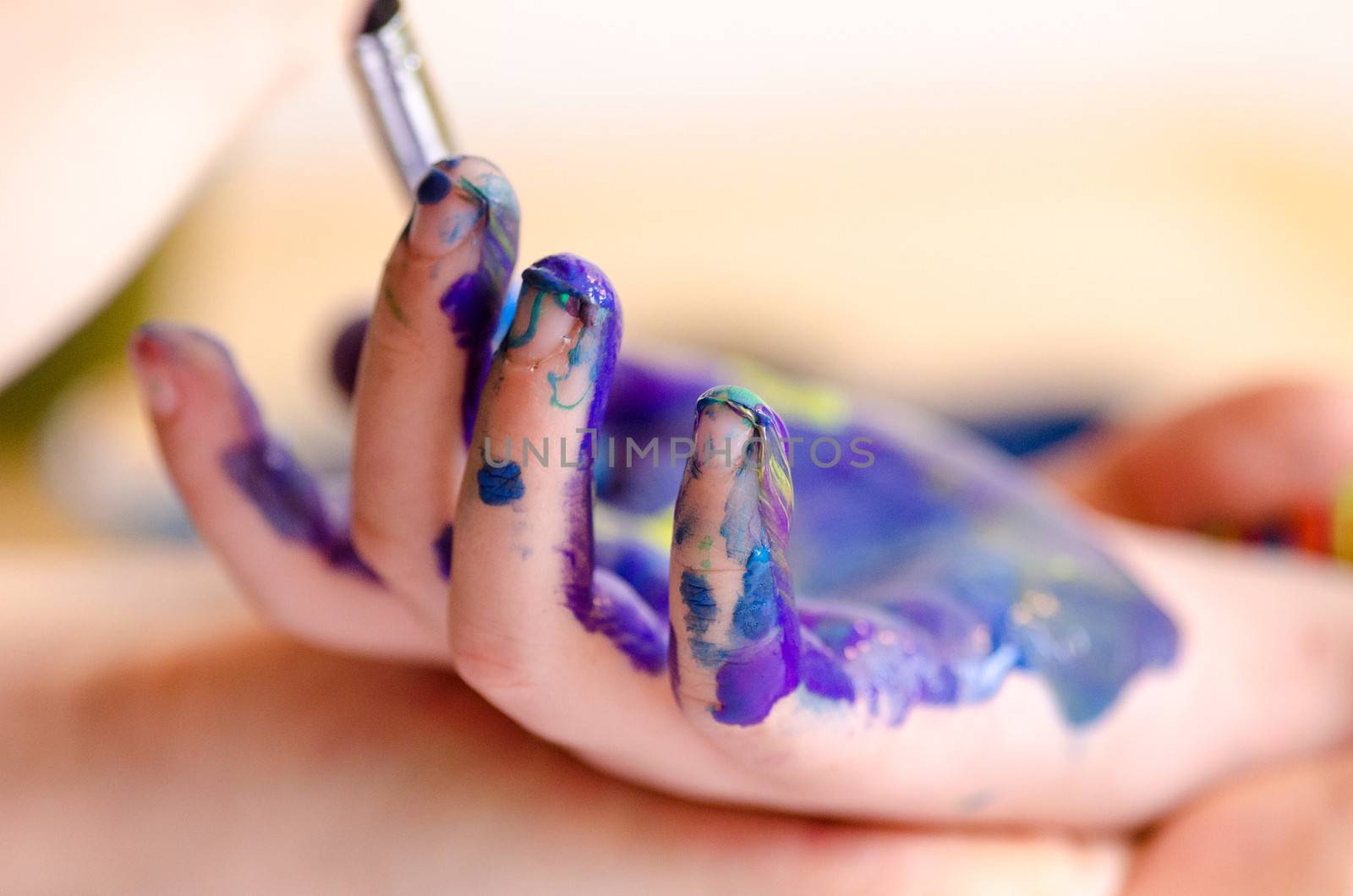 Child painting its hands in order to make a print on paper