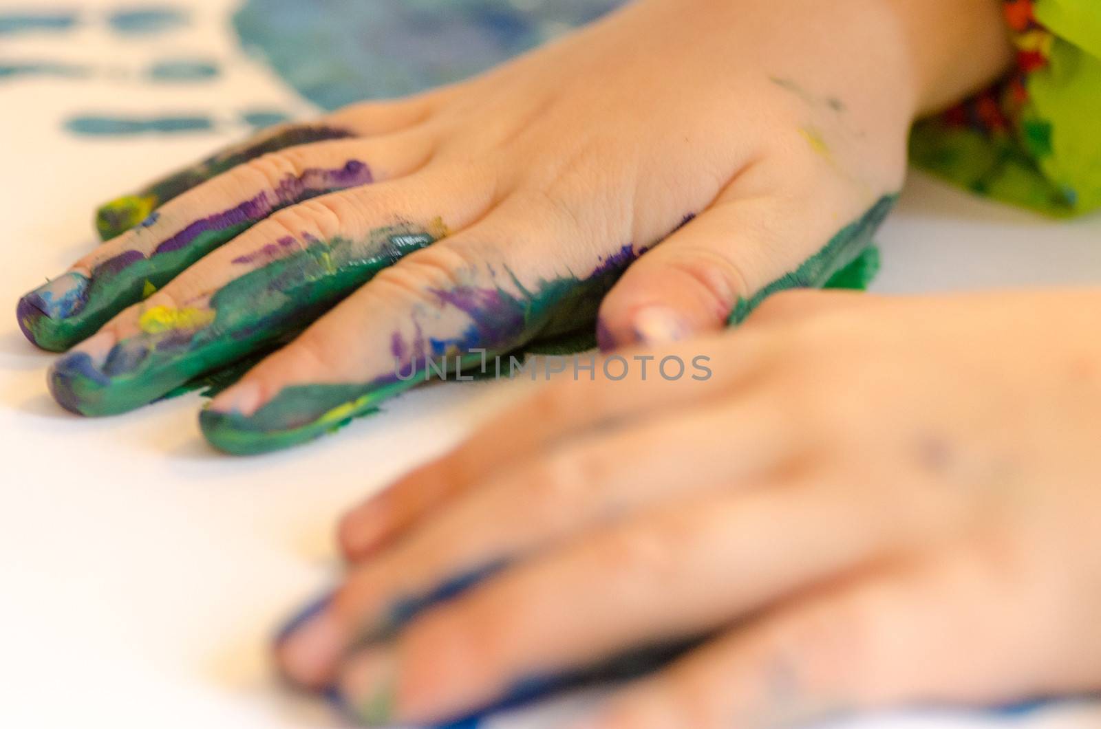 Child painting its hands in order to make a print on paper