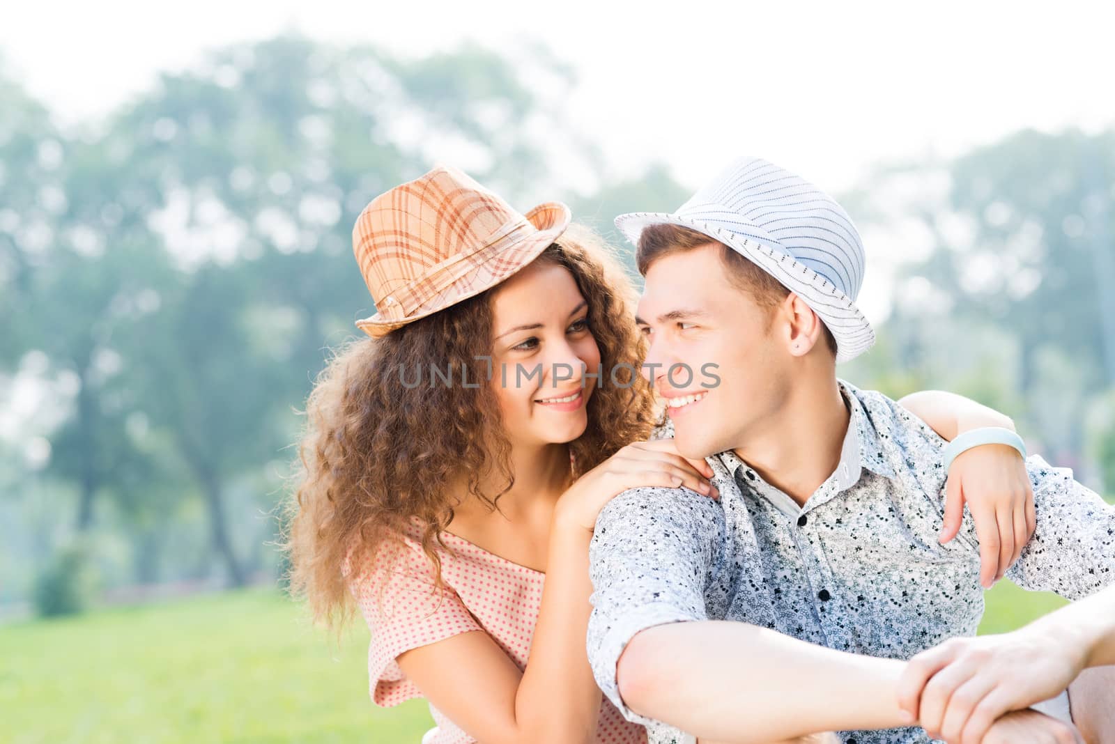 romantic couple lying on the grass in the summer park, spending time with loved ones