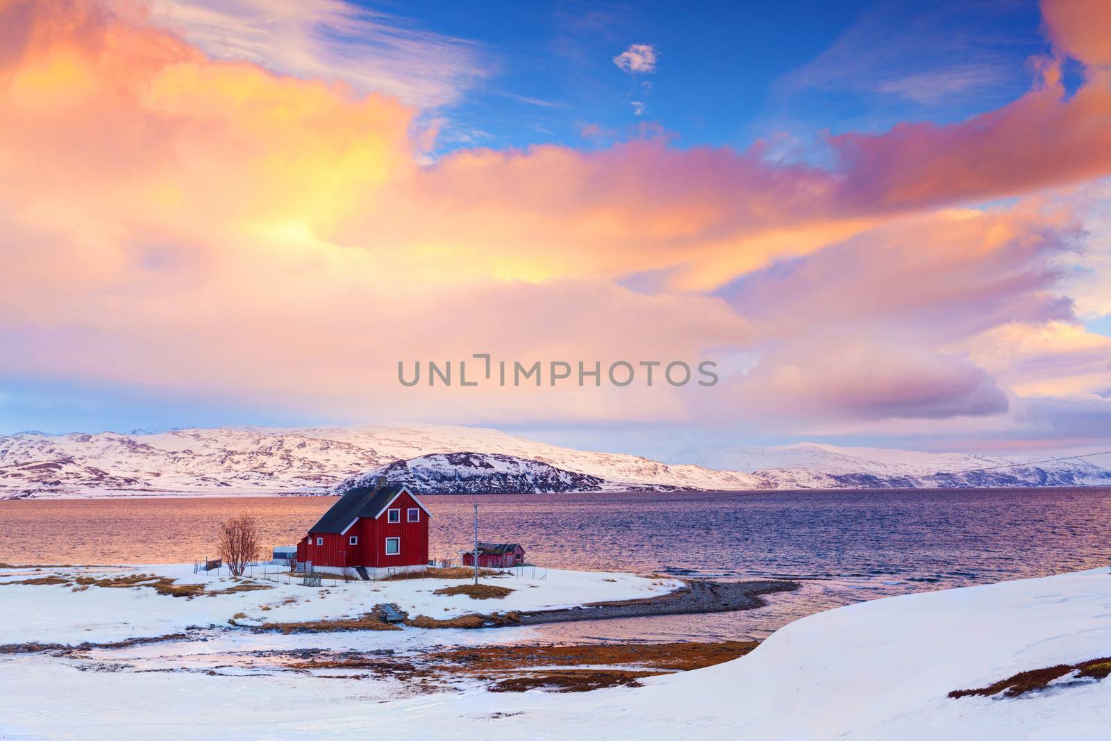 Norway in winter: mountains with colorful houses and the ocean at sunset.