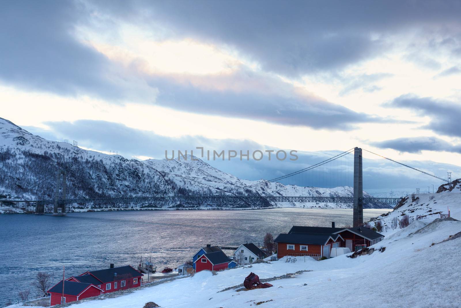 Norway in winter: mountains with colorful houses and the ocean at sunset.