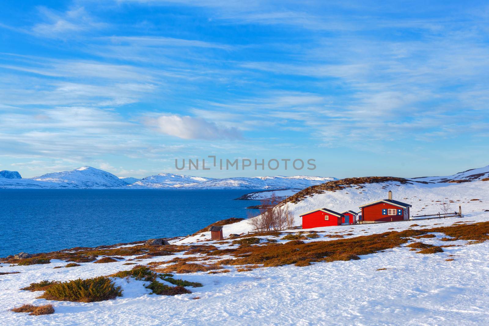 Norway in winter: mountains with colorful houses and the ocean on a sunny winter day.