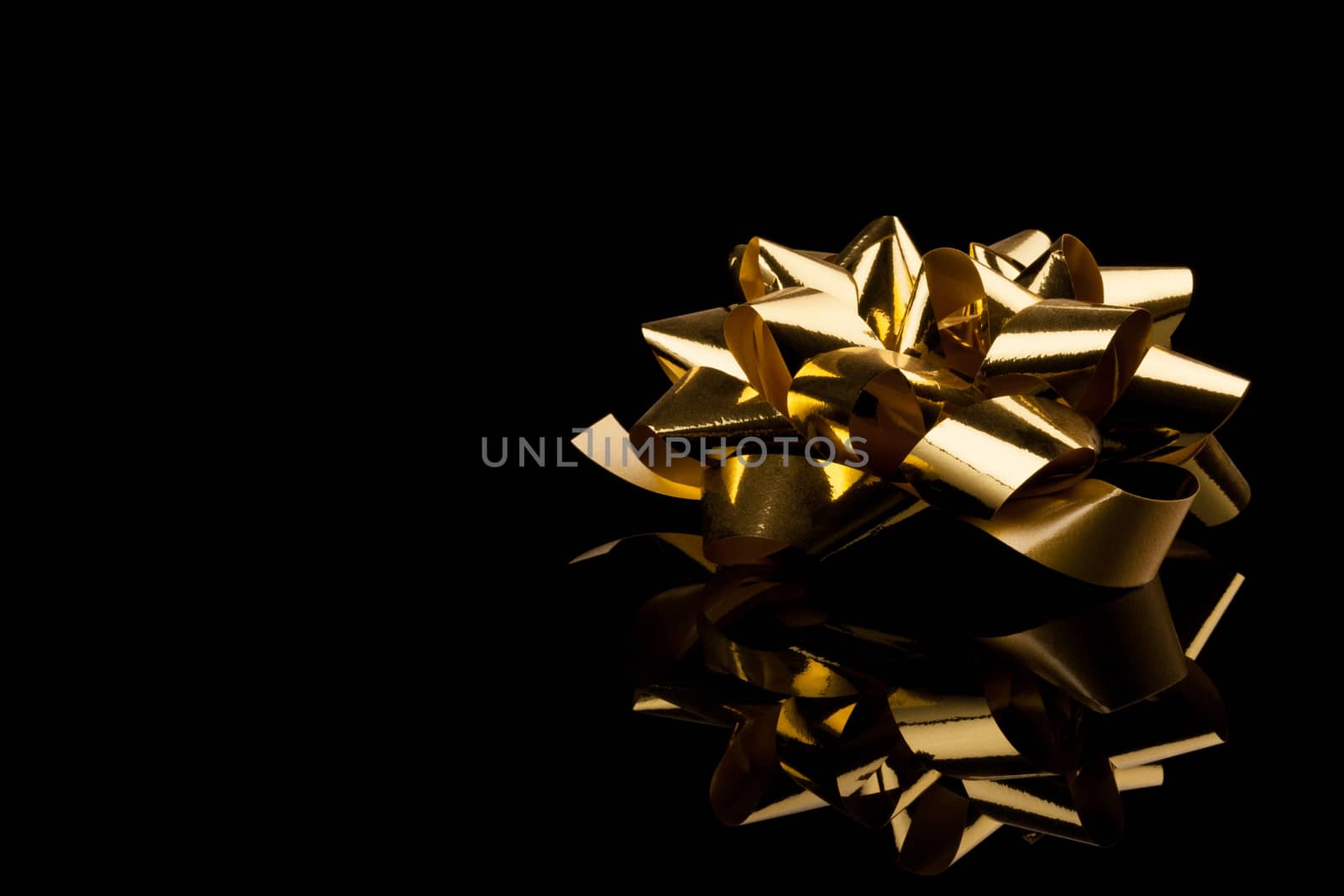 golden gift bow with reflection on black background