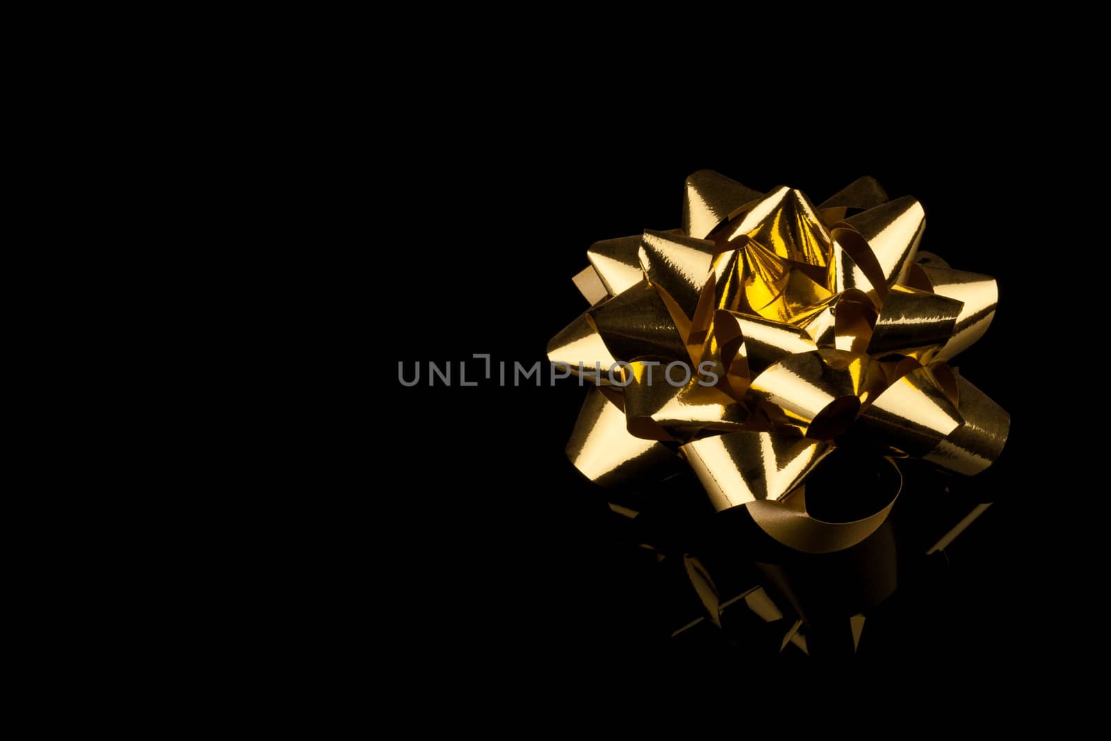 golden gift bow with reflection on black background