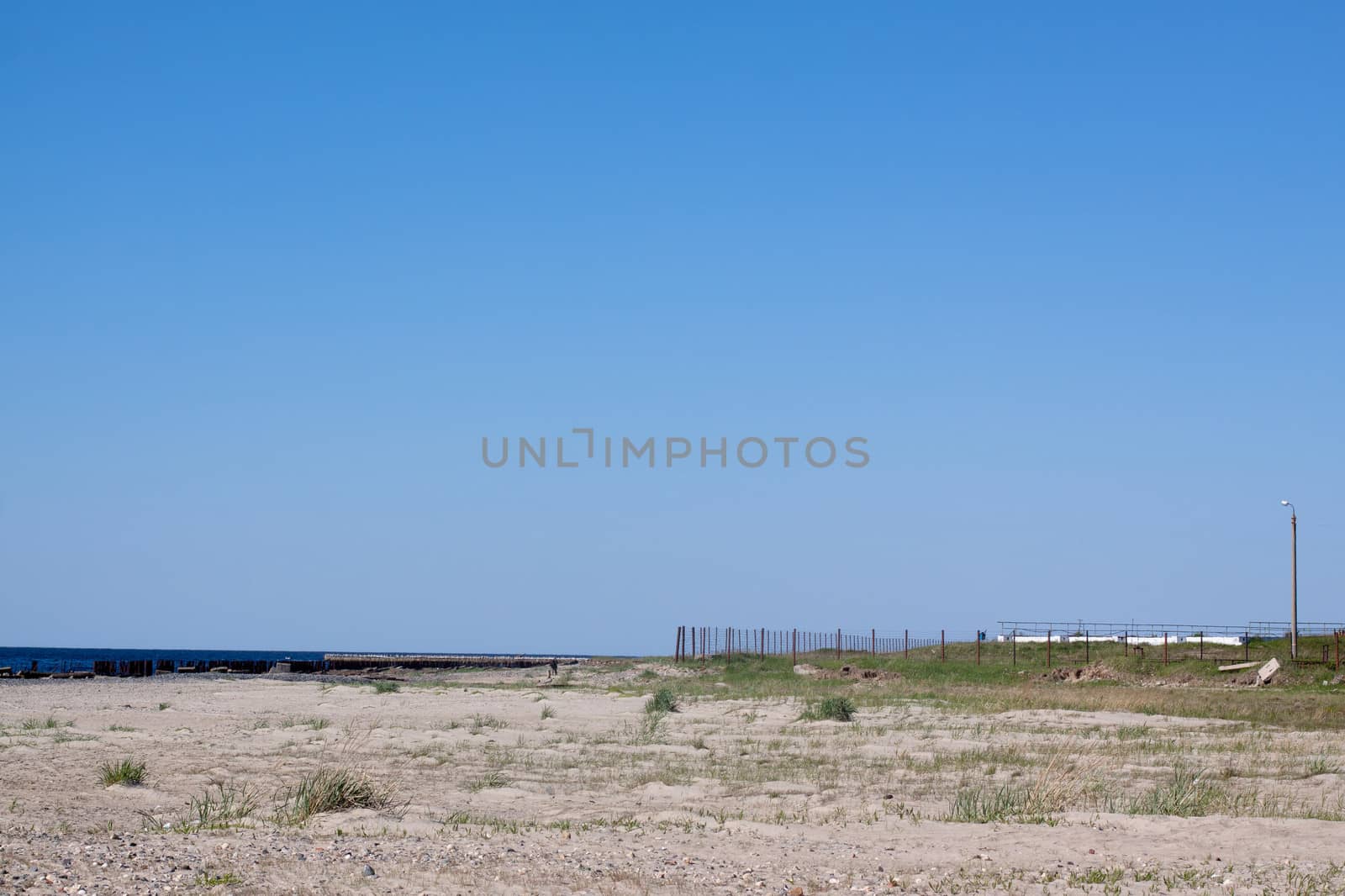 A landscape with sea, sand, fence and sky in sunny day
