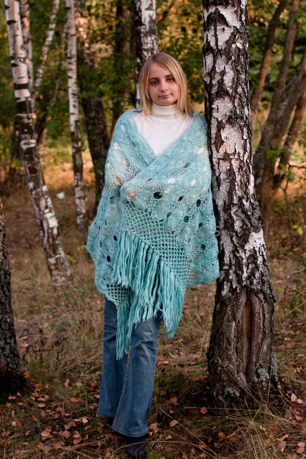 A standing girl in a swal and jeans in a forest
