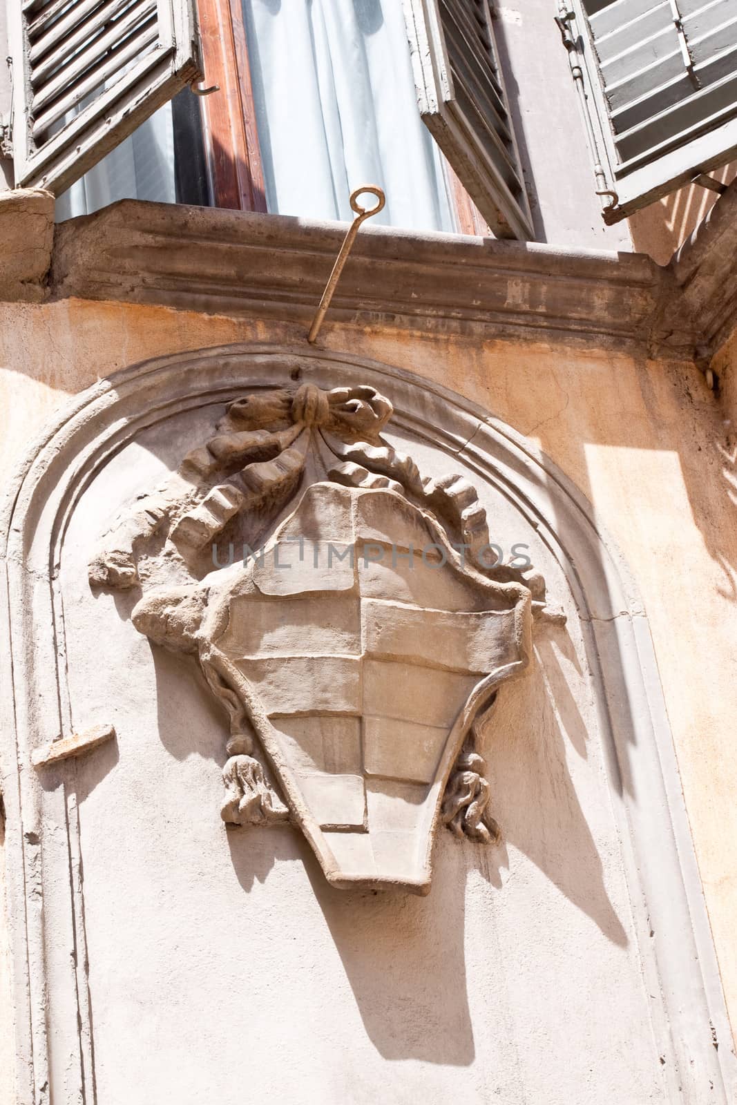 Stone coat of arms on a wall under a window
