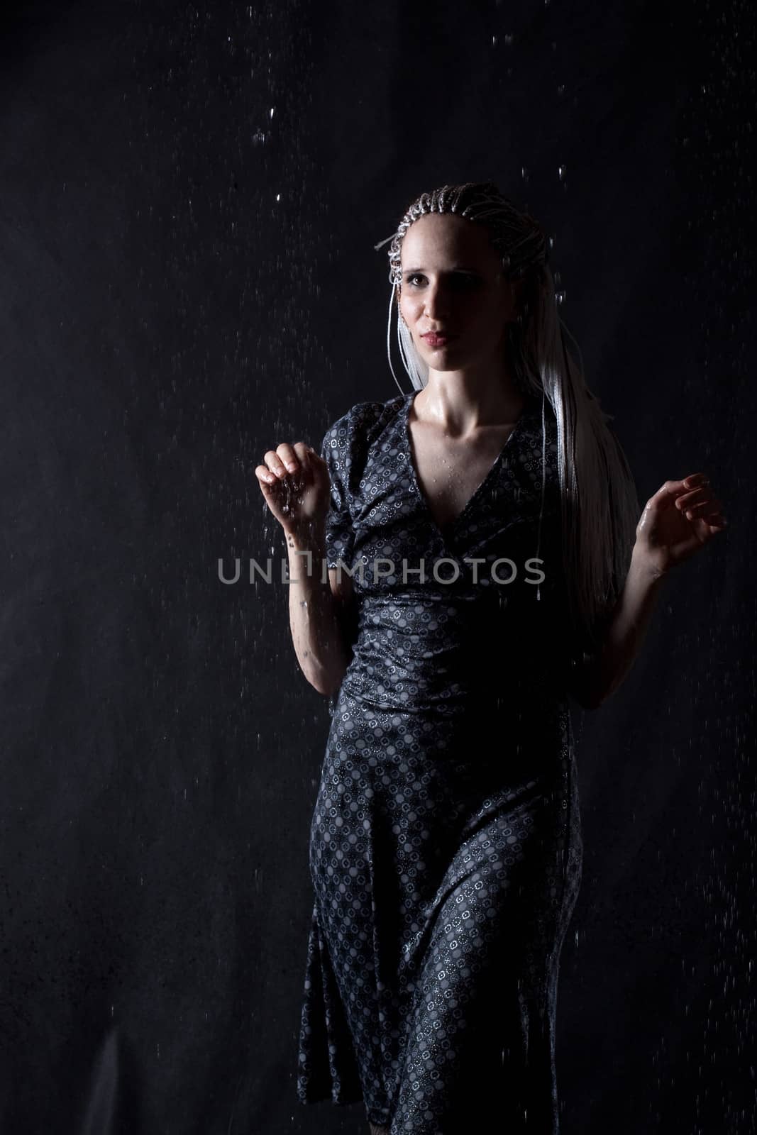 girl in grey dress in the rain on black background 
