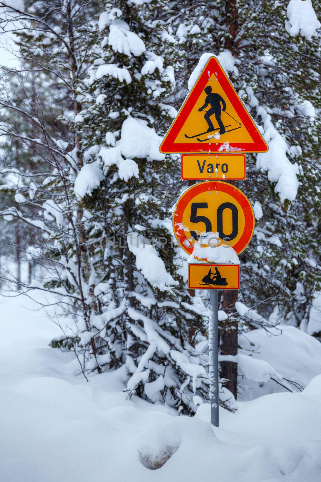 Warning traffic sign on snowy arctic winter road.